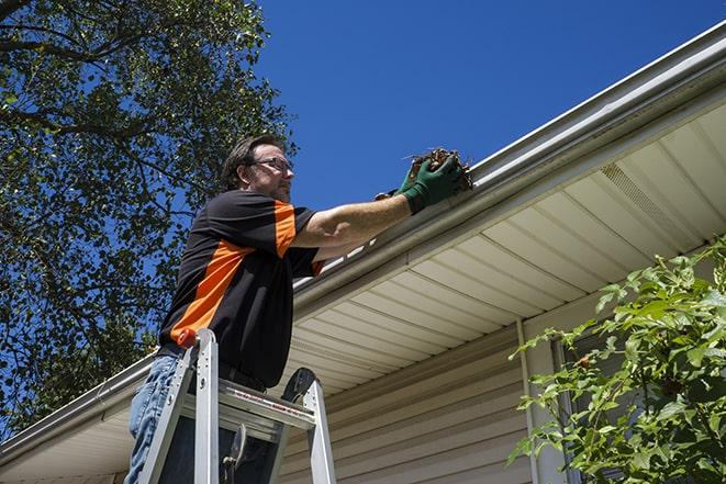 worker installing new gutter system on a roof in Black Creek